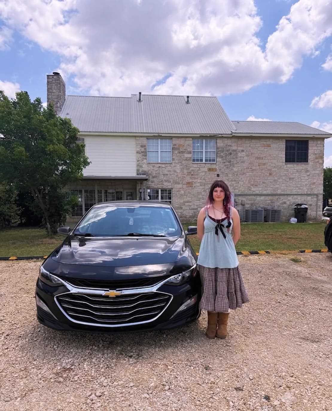 A customer standing next to the black Chevrolet Malibu she bought.