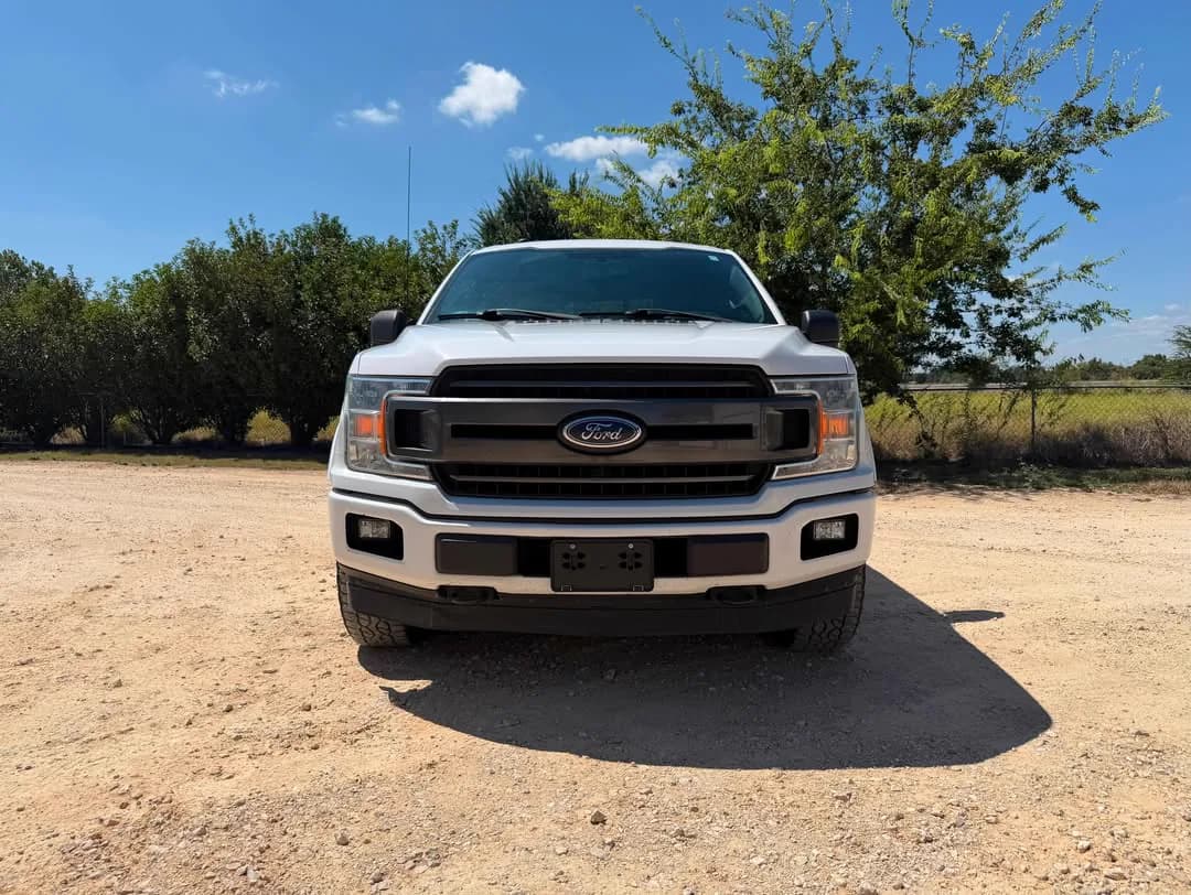 The white Ford F-150 photographed head-on on the gravel lot.